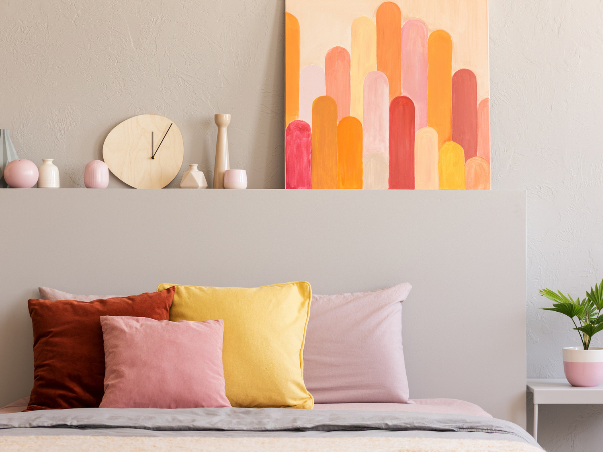 Cozy Tenant living space showcasing a neatly styled bed, decorative pillows, and vibrant wall decor