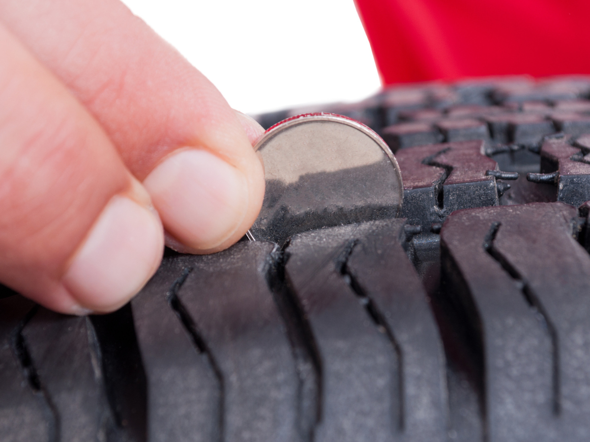 Coin measuring ATV tire tread depth to assess tire wear and maintain safe off-road performance