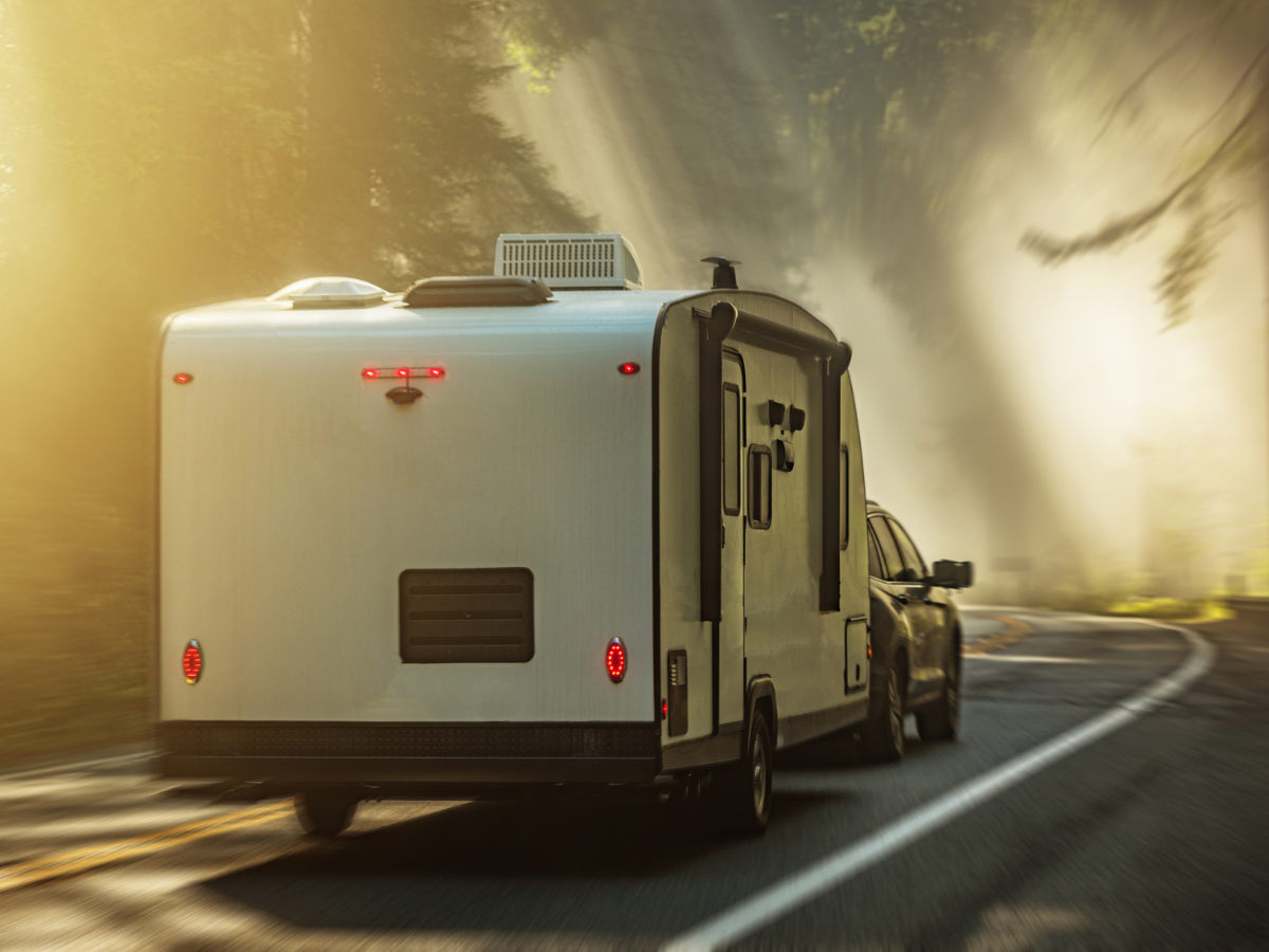 Travel Trailer being towed through a forest highway, ready for Camp adventures and outdoor travel