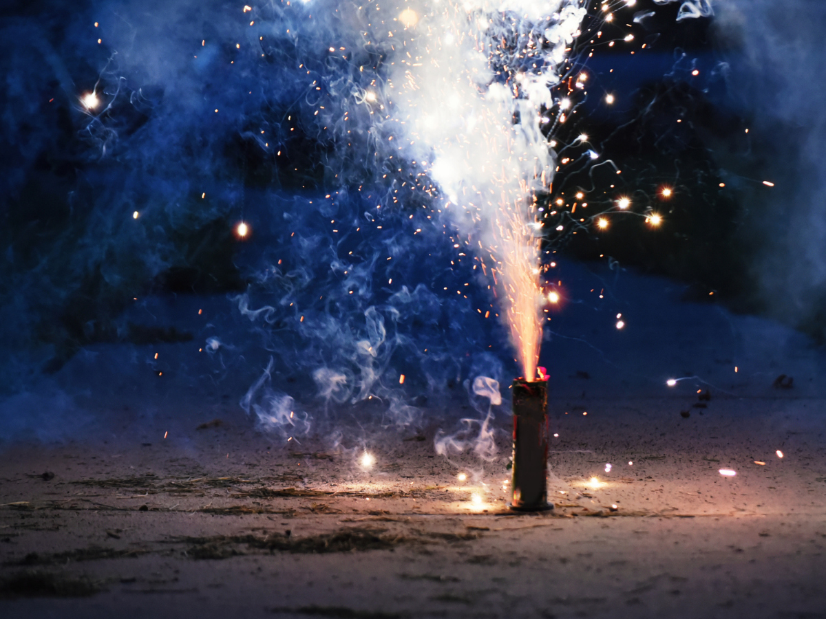 Single Firework emitting sparks and smoke during an outdoor nighttime display.