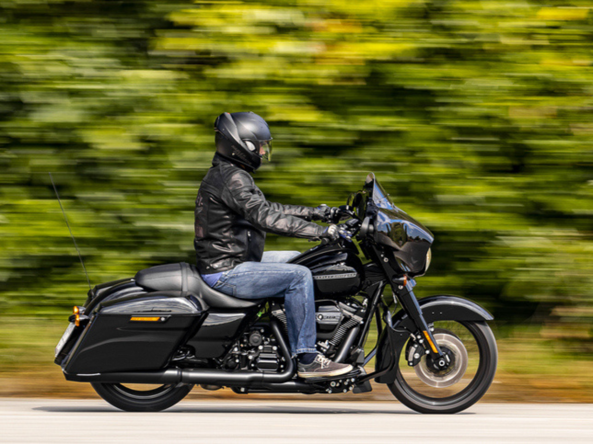 Black Motorcycle rider traveling along a tree-lined road with motion blur in the background