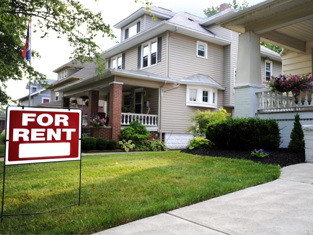 For Rent sign on the lawn in front of a suburban house with a covered porch