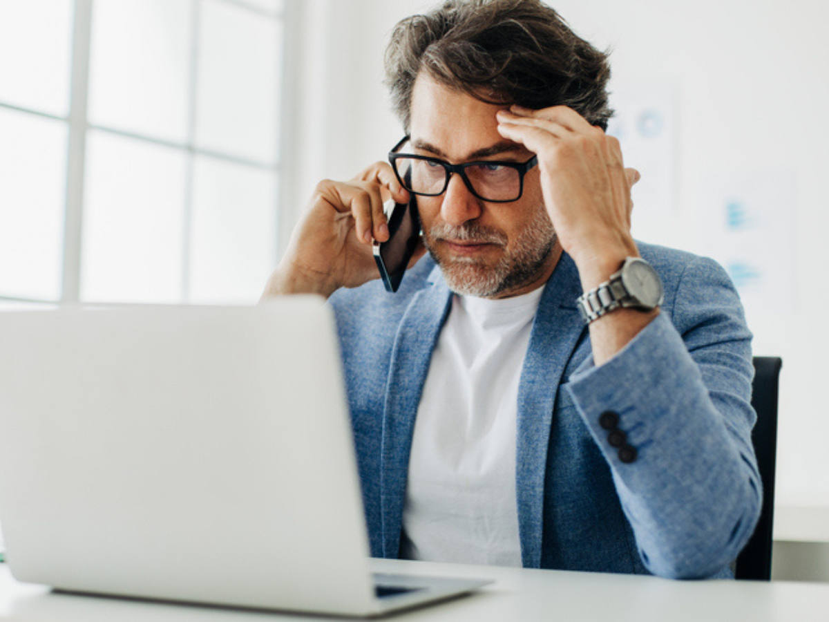 Concerned business owner on the phone looking at laptop, illustrating the misconception that business insurance is too expensive.