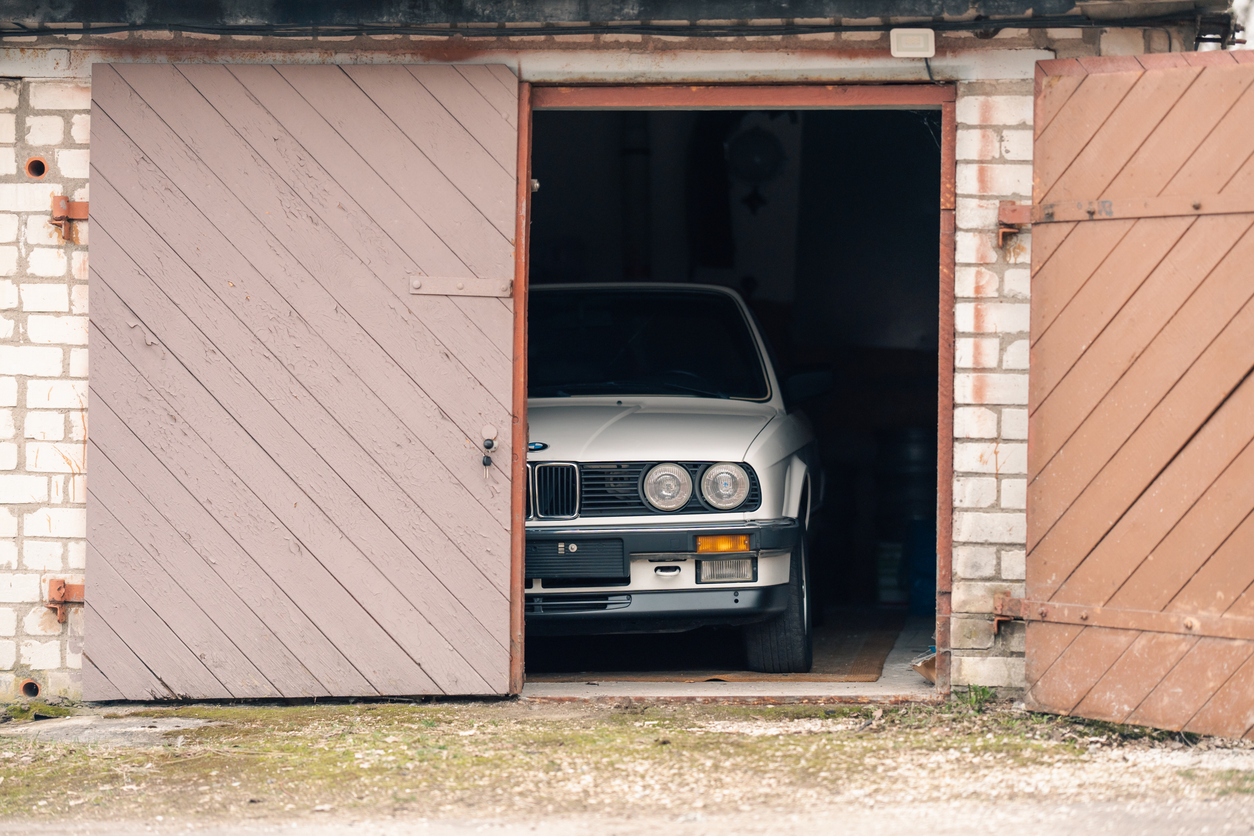 Restored car stored inside a garage with wooden doors, highlighting secure storage for classic vehicle insurance