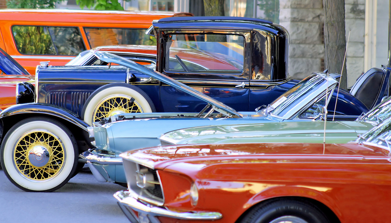 Row of restored classic cars parked outdoors with hoods open, showcasing vintage vehicle condition for insurance and appraisal
