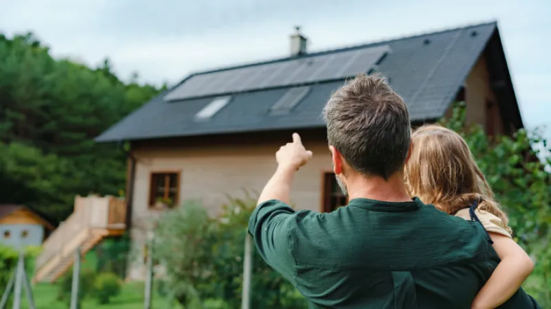 Father and Daughter pointing at sustainable home with solar panels while having Sandbox coverage