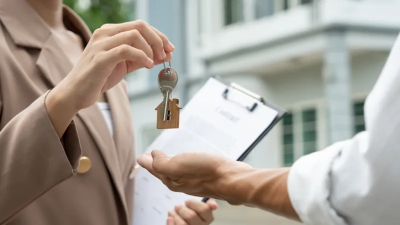 Landlord handing over apartment keys to new tenant during rental agreement signing, representing tenant insurance coverage, renter coverage, and apartment insurance protection.