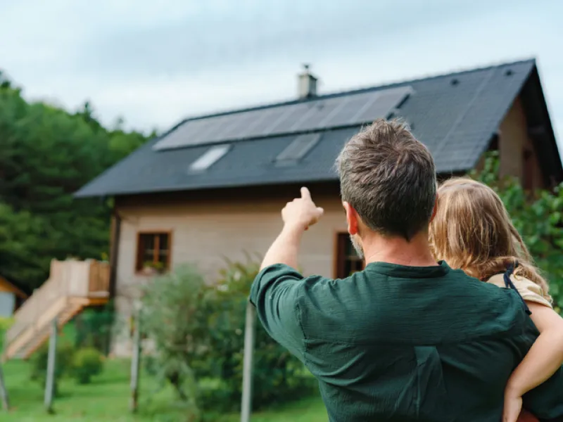Father and Daughter pointing at sustainable home with solar panels while having Sandbox coverage